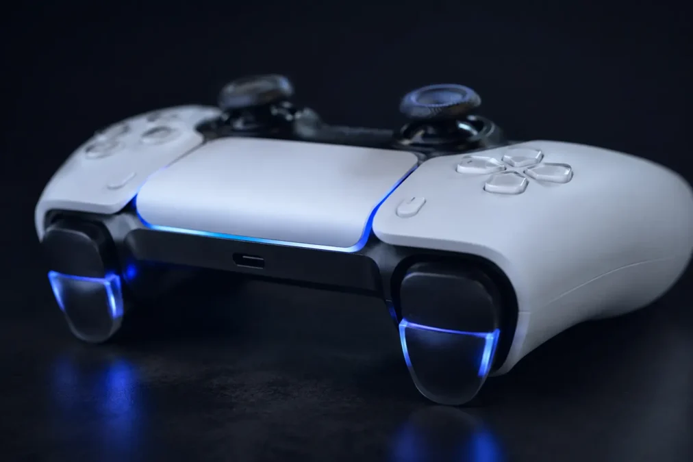Controle profissional ps5 sem fio para console com gatilhos adaptativos iluminados em azul sobre superfície escura com iluminação dramática lateral.