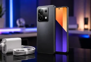 Celular redmi note 13 pro exibindo módulo de câmeras traseiro sobre superfície reflexiva ao lado de carregador rápido de sessenta e sete watts