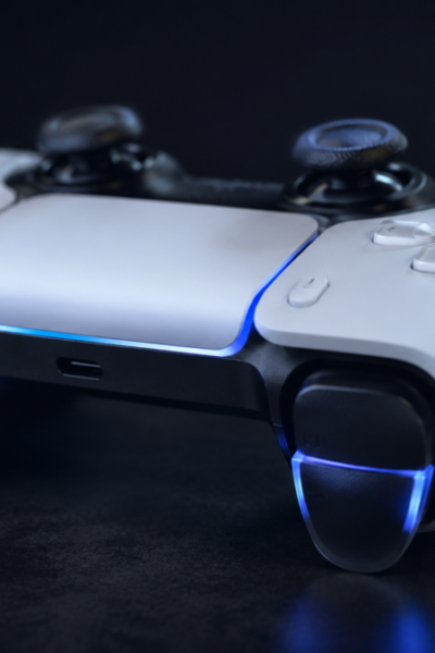 Controle profissional ps5 sem fio para console com gatilhos adaptativos iluminados em azul sobre superfície escura com iluminação dramática lateral.
