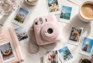 Dispositivo fotografico do tipo camera instax mini 12 rosa cercado por fotos instantaneas reveladas sobre mesa de madeira