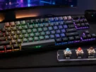 Periférico do tipo teclado mecanico gamer com luzes RGB acesas sobre mesa de computador de jogos