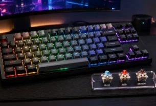 Periférico do tipo teclado mecanico gamer com luzes RGB acesas sobre mesa de computador de jogos