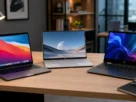Três notebooks modernos de marcas diferentes abertos em uma mesa de trabalho de madeira.